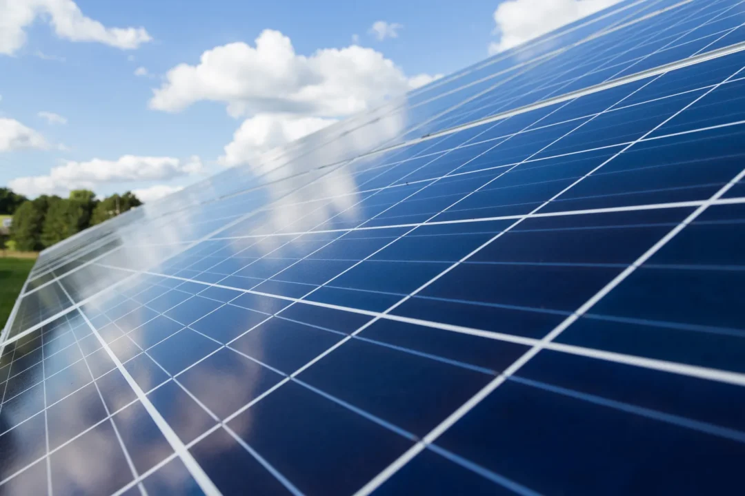 Close-up of blue solar panels reflecting clouds under a bright sky, highlighting renewable energy technology in an outdoor setting. Close-up of blue solar panels reflecting clouds under a bright sky, highlighting renewable energy technology in an outdoor setting.